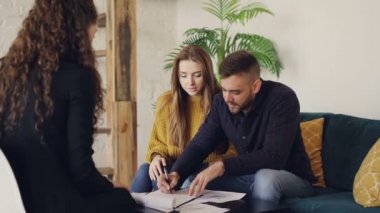 Genç adam emlakçı ile el clasping sonra eşi öpüşme imzalama ev anahtarı, belge ve alarak konut aracıya, konuşuyor. Satın alma gayrimenkul ve insanlar kavramı.