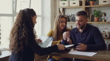 Genç eş belgelerin imzalanması ve Emlak anahtarları sonra başarılı anlaşma yeni sahiplerine verilmesi sonra laptop ile çalışma öpüşme daire satın alıyor.