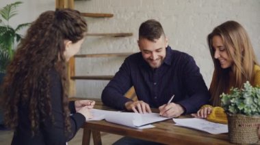 Genç insanlar gülüyor ve imzalama satın almak ve sözleşme sonra Emlak ile toplantıda anahtar ve sarılma alarak satış. Satın alma ve mülkiyet kavramı satış.
