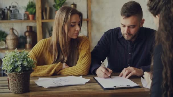 Όμορφος άντρας σπίτι αγοραστής είναι υπογραφή σύμβασης πώλησης με τον πράκτορα στέγαση, να πάρει το κλειδί και αγκαλιάζει την κοπέλα του μετά από να κάνει προσφορά με realtor. Αγοράζοντας ακίνητη περιουσία έννοια. — Αρχείο Βίντεο