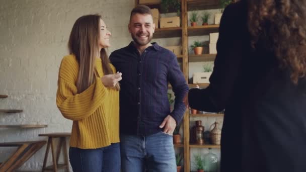 Slow motion voor onroerend goed kopers getting sluitsteen van huisvesting agent na succesvolle deal, zoenen en knuffelen met geluk en schudden handen aan vrouwelijke makelaar. — Stockvideo