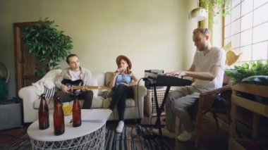Güzel şarkıcı arkadaşlarıyla müzik aletleri klavye ve gitar ev stüdyosu prova sırasında oynarken sözleri ile gazetede arıyorum şarkı söylüyor.