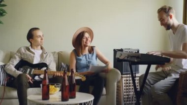 Neşeli arkadaşlar müzisyenlerin tartışırken müzik evde prova sırasında söz ediyoruz. Vokalist ve gitarist dinleme ve konuşma yaparken keyboarder pratik.