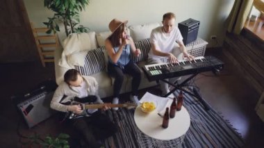 Müzik grubu ev stüdyosunda prova yüksek açılı görünüş. Aktif duygusal genç insanlar iskambil müzik aletleri klavye ve gitar ve şarkı vardır.