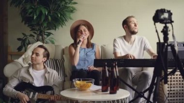 Müzik grubu evde pratik ve onların online blog için fotoğraf makinesinde antrenmanlarını internet kayıt. Vokalist şarkı söylüyor, klavyecisi ve gitaristi oynuyorlar.