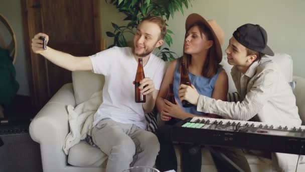 Jeune homme barbu tient smartphone et prendre selfie avec ses amis musiciens tenant des bouteilles. Amitié, personnes créatives, technologie moderne et concept amusant . — Video