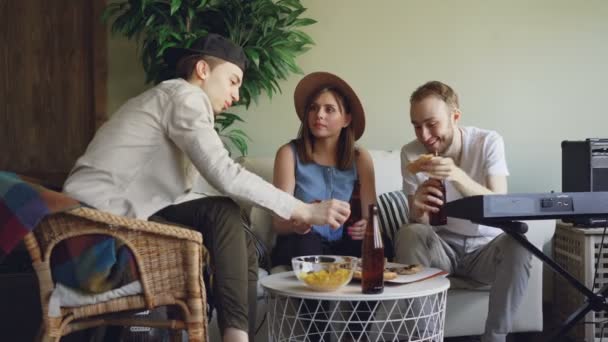 Músicos de sucesso estão comemorando um novo álbum de brindes, batendo garrafas, comendo pizza e bebendo cerveja após o ensaio em estúdio em casa. Conceito de amizade e comida . — Vídeo de Stock