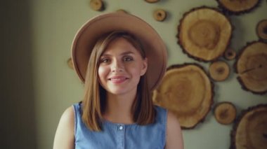 Yavaş hareket olan çekici genç kadın sarışın saç moda şapka ve kameraya bakarak, gülerek ve gülümseyerek denim üst giyiyor. İnsanlar ve olumlu duygular kavramı.