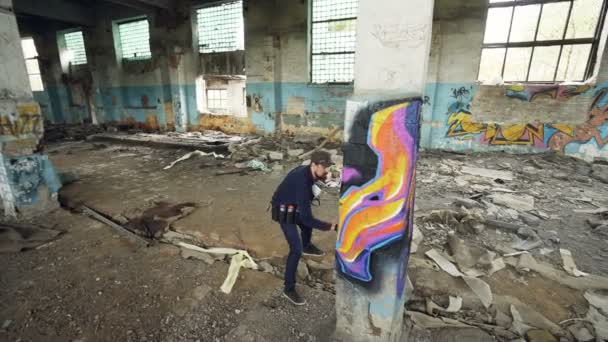 Imagen de alto ángulo del joven pintor urbano creando una imagen abstracta sobre una columna en un antiguo edificio dañado. Arte moderno, artista callejero, creatividad y concepto de personas . — Vídeos de Stock