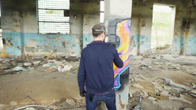 Hızlandırılmış sanatçılar grafiti süslemek için sprey boya kullanarak modern grafiti resimleri ile endüstriyel bina terk. Yaratıcılık, sokak sanatı ve insanlar kavramı.