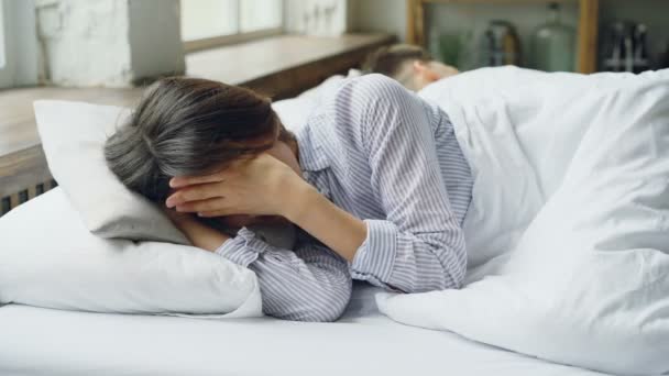 Mujer triste es pijama está acostado en la cama y llorando después de la pelea con su marido que está acostado a su lado con la espalda a ella. Dificultades en el concepto de vida matrimonial . — Vídeo de stock