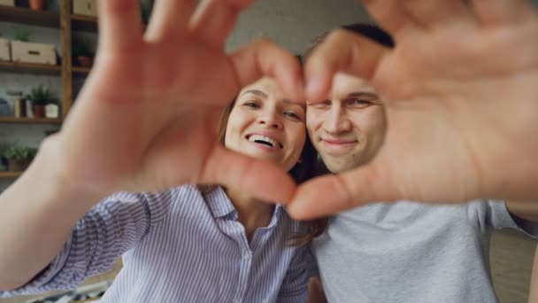 Retrato de alegre pareja multiétnica haciendo corazón con las manos, mirando a la cámara y sonriendo. Relación romántica, vida matrimonial y concepto de luna de miel . — Vídeo de stock