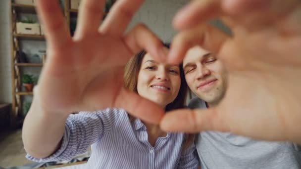 Lassú mozgás portréja boldog többnemzetiségű pár, így a szív a kezüket, látszó-on fényképezőgép, és mosolyogva. Romantikus kapcsolat, a házas élet és a nászút koncepció. — Stock videók