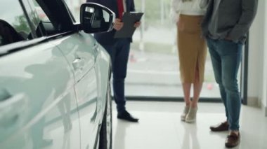 Bayilik yeni araba satın alma ve takım elbiseli yararlı Yöneticisi konuşmak müreffeh kişi genç çift düşük doz. Parlak lüks araba ön planda, arka planda büyük pencere olduğunu.