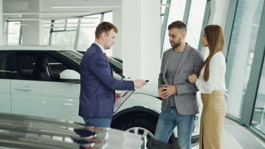 Yakışıklı erkek araba alıcı anahtar fob dostu satıcı ve ona elini sıkarken o zaman öpüşme ve çekici kız arkadaşı otomatik yanında dururken sarılma oluyor.