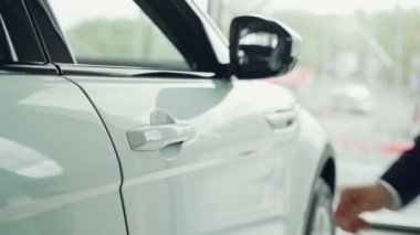 Erkek el araba satışı ile arka planda büyük pencere içinde arabanın kapısını açarak yakın çekim shot. Satış otomobil, lüks otomobiller ve satış temsilcisi kavramı.