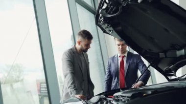 Profesyonel otomobil satış elemanı müşteri araba motoru motor kaputu altında sergiliyor, erkekler otomobil parçaları seyir ve konuşuyor. Alış ve satış araçlar kavramı.