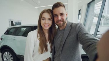 Genç çift bakış açısı çekim online vidoe içinde araba bayilik araba satın aldıktan sonra ara var. Adam kamera tutuyor ve kadın konuşmak ve öpüşme anahtarları, gösterilen.