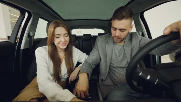 潜在的汽车买家夫妇正在检查汽车内部坐在前排座椅持有方向盘和触摸汽车零件 购买车辆与关系概念 — 图库视频影像