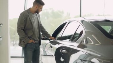 Şık adam lüks araba yürüyüş ve içinde araba bayilik dokunmadan yeni otomobil seçmektir. Zengin insanlar, ulaşım ve iş sınıf araçlar kavramı.