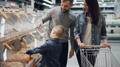 Yararlı oğlu ailesi ekmek satın almak için yardımcı oluyor, baba açılış kapsayıcıdır ve çocuk somun alarak ve arabası içinde koyarak kokulu. Birlikte alışveriş kavramı.