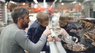 Baba ve küçük oğlu gıda süpermarkette, camı adam ürünleri dönük, gülüyor ve oğlu için çocuk gülümsüyor merak konuşmak arıyoruz.