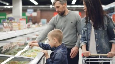 Modern aile düzenleyeceğim dondurulmuş gıda süpermarkette satın alma, çocuk buzdolabı ve alarak çanta açıyor, ailesi son kullanma tarihi ve malzemeler içeriği kontrol ediyor.