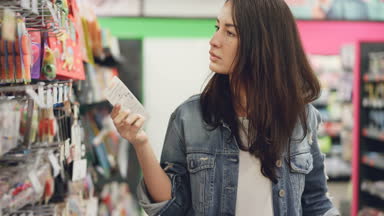 Çekici genç kadın Doğum günü mumları süpermarkette satın alıyor, o mal, onlara bakmak ve bunları karşılaştırarak alıyor. Alışveriş ve insanlar kavramı.