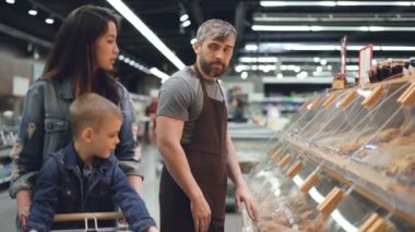 Tezgâhtar süpermarkette ekmek bölümünde ambalaj ekmek rulo daha sonra güzel aile anne ve oğlu için çalışma ve yiyecek çekici kadın için veriyor.