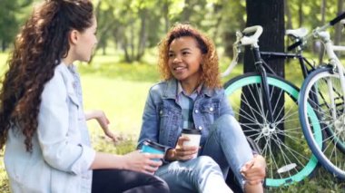 İki kadın bisikletçiler park ve bisiklet sürme sonra sohbet çimenlikte oturan dinlenme İçme çok ciddiyim. Aktif yaşam tarzı, modern genç insanlar ve eğlence kavramı.