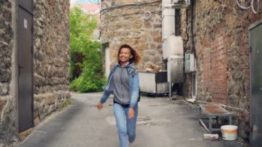 Yürüyüş ve sokakta dans sonra kameraya bakıyor ve gülümseyen mutlu Afrikalı-Amerikalı genç portresi. Neşeli aktif insanlar ve mutluluk kavramı.