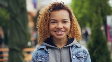 Gülümseyen, gülen ve yaz aylarında güzel yeşil park onu saç ayakta dokunmadan kameraya, seyir çekici Afro-Amerikan Kız portresi Slowmotion.