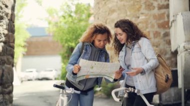 Haritaya bakıyordum ve ayakta Bisiklet ile yabancı şehirde sokakta konuşmak güzel kızlar turist Slowmotion. Bisiklet turizm seyahat yurtdışında ve insanlar kavramı,.