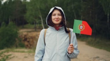 Ağır çekim gülümseyen ve kameraya bakarak Portekiz, bayrak tutan çekici Portekizce kız portresi. Vatandaşlar, ulusal gurur, bahar kavramı.