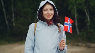 Ağır çekim portre resmi ormanda ayakta ve gülümseyen Norveç bayrağı sallayarak çekici Norveçli spor fan. İnsanlar, Milliyet ve ülke kavramı.