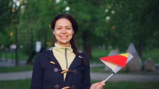 Retrato en cámara lenta de una chica bonita con ropa casual sonriendo y ondeando la bandera belga mirando a la cámara felizmente. Mujeres jóvenes, ciudadanos felices, concepto de países europeos . — Vídeos de Stock