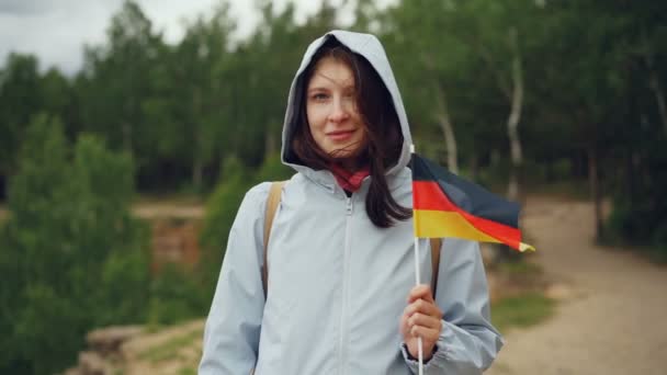 Ritratto al rallentatore di attraente donna tedesca che tiene la bandiera della Germania, sorridendo e guardando la macchina fotografica. Patriottismo, cittadino orgoglioso e concetto di popolo . — Video Stock