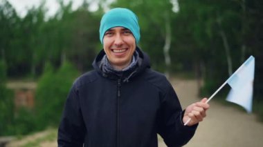 Ağır çekim portre mutlu Arjantinli spor fan ceket ve mutlu gülümseme ile Arjantin bayrağı sallayarak şapka giyiyor. Favori takım ve milliyetçilik kavramı.