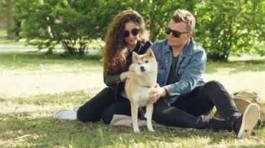 Karı koca mutlu çiftimiz parkta çim üzerinde oturan ve konuşurken onların evde beslenen hayvan shiba Inu köpek yavrusu Füssing. Konuşma, hayvanlar ve modern yaşam kavramı.
