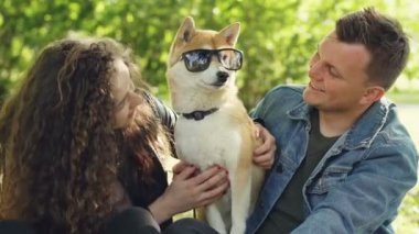 Mutlu insanlar sevgi dolu evde beslenen hayvan mülkiyet köpek güneş gözlüğü Füssing sonra o öpüşme ve parkta güneşli günde eğlenirken gözlük köpekler gözleri kapalı alarak.