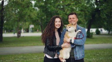 Ağır çekim portre sevimli çift ve birlikte parkta duran ve gülümseyerek kameraya bakarak safkan köpek. Doğa ve Aile kavramı.