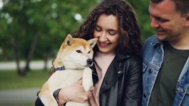 Ağır çekim güzel safkan köpek tutarak, bakmak ve onun pençe sallayarak sonra burnu dokunmadan mutlu çift. Sevgi dolu sahipleri, mutlu hayvanlar ve doğa kavramı.