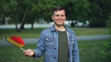 Ağır çekim portre Belçika bayrağı sallayarak, kameraya bakıyor ve gülümseyen ifade yüzü ile duygusal biri. Milliyet, ülke ve vatanseverlik kavramı.