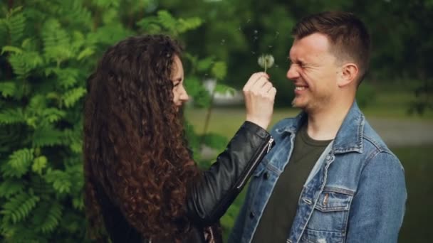 Mouvement lent de deux personnes attrayantes amoureux heureux jouer avec le pissenlit blowball s'amuser dans le parc le week-end et rire. Couples et concept de nature . — Video