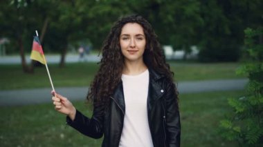 Ağır çekim portre Almanya bayrağı sallayarak ve gülümseyerek kameraya bakarak çok Alman kadın spor fan. Avrupa ülkeleri, milletten ve insanlar kavramı.