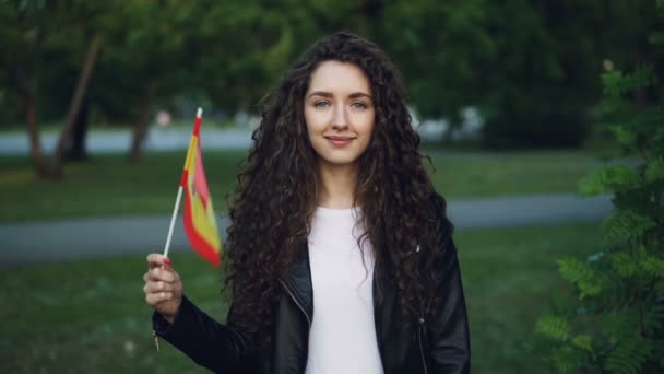 Zpomalený pohyb portrét šťastná žena španělské hrdý vlastenec mává oficiální vlajkou Španělska při pohledu na fotoaparát a usmívá se. Občanství, sportovní fanoušky a koncepce cestovního ruchu. — Stock video