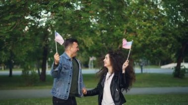 Amerikan bayrağı atlama, gülen ve güzel park ağaç ve çimenler arka planda birbirine bakarak heyecanlı gençlerin portresi ağır çekim.