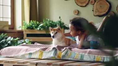 Genç kadın güzel köpek yavrusu okşayarak ve bu iken onlar yatağa birlikte dinlenme modern düz yalan sevgi ifade etmek için konuşuyor. Sevgi dolu hayvanlar ve gençlik kavramı.