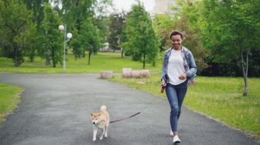 Ağır çekim bir şehir parkı doğa, özgürlük ve açık hava etkinliği zevk güzel küçük köpek ile çalışan mutlu karışık yarış kız. Sağlıklı yaşam konsepti.