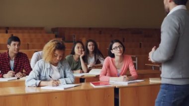 Lise öğrencilerinin ders erkek öğretmen ile yaşıyorsanız, yazma ve masalarda oturan öğretmen konuşurken genç insanlar. Millennials, Yükseköğretim ve kolejler kavramı.